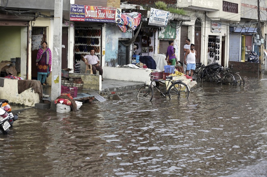 Varias personas observan una calle inundada en Amritsar (India)