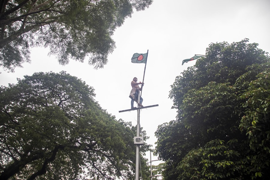 Un manifestante sostiene la bandera nacional de Bangladesh en un poste de la calle, durante una manifestación en el Central Shaheed Minar en Dhaka, Bangladés.