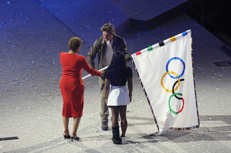 La alcaldesa de Los Angeles, Karen Bass (i), y la gimnasta Simone Biles, entregan la bandera olímpica actor estadounidense Tom Cruise durante la ceremonia de clausura de los Juegos Olímpicos de París 2024 celebrada este domingo, en el Estadio de Francia en Saint-Denis (Francia)