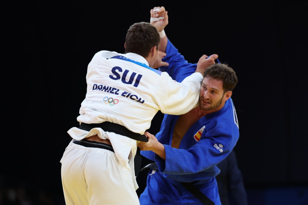 El español Niko Shera (azul) combate contra el suizo Daniel Eich en la ronda de cuartos de final de la categooría -100kg en judo masculino en el marco de los Juegos Oímpicos París 2024.