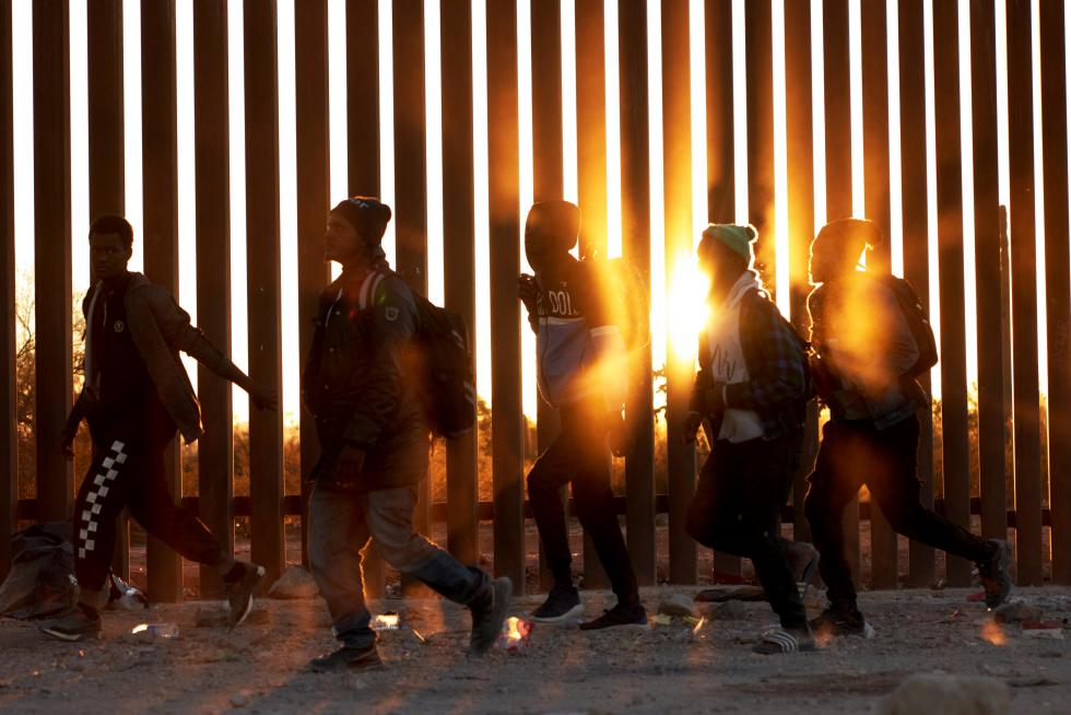 Migrantes caminan junto al muro en la frontera de EE.UU, y México en Lukeville, Arizona, en una fotografía de archivo. EFE/ Allison Dinner