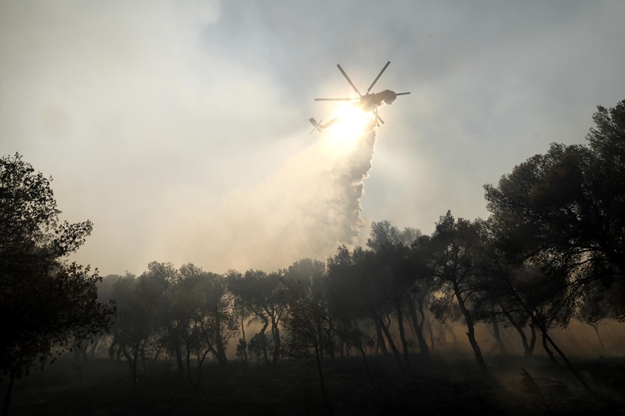 Un helicóptero esparce agua sobre el incendio declarado en Patima Halandri, a las afueras de Atenas