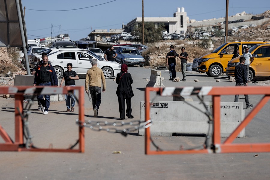 Un grupo de personas se dirige caminando hacia la carretera para cruzar desde Qilqis hasta Hebrón, en los territorios ocupados de Cisjordania, después de que el Ejército israelí cortara los accesos al tráfico rodado a ambas ciudades