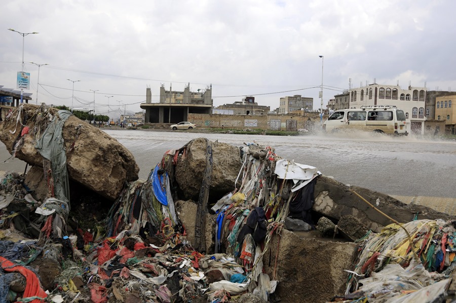 Un autobús recorre un arroyo inundado lleno de desechos causados ​​por las fuertes lluvias, en Sana'a