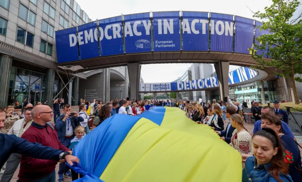 Bruselas (Bélgica), 23/08/2024.- La gente sostiene una gran bandera ucraniana durante una ceremonia del Parlamento Europeo para celebrar el Día de la Bandera Nacional de Ucrania en Bruselas, Bélgica, el 23 de agosto de 2024. La misión de Ucrania ante la UE celebró el día de la bandera nacional del país en la Explanada Solidarnosc 1980, con el Vicepresidente del Parlamento Europeo, Wilmes, y el Comisario de Mercado Interior, Breton, pronunciando discursos de apertura. (Bélgica, Ucrania, Bruselas) EFE/EPA/OLIVIER HOSLET