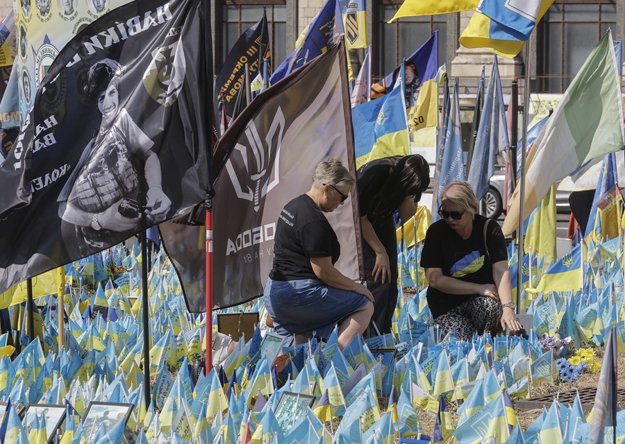 mujeres ucranianas reaccionan entre las banderas nacionales ucranianas colocadas para conmemorar a los soldados ucranianos caídos en la Plaza de la Independencia, en Kiev