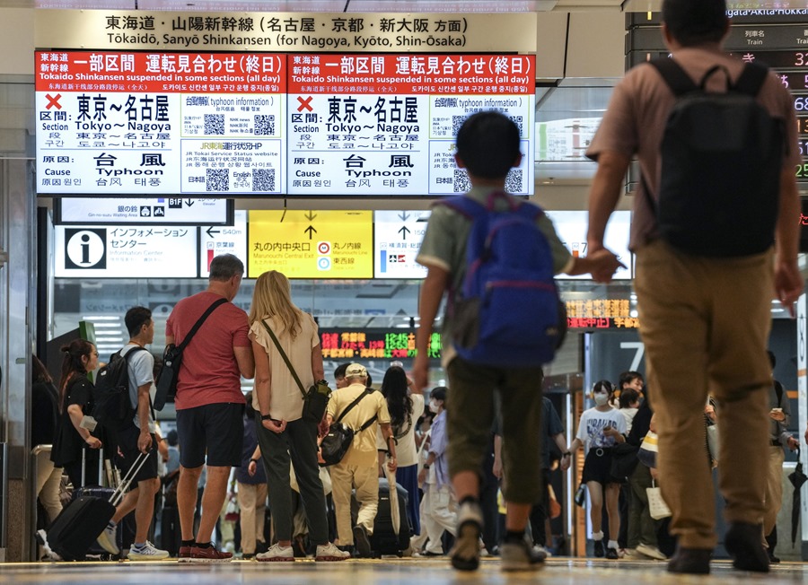 os pasajeros caminan frente a pantallas que muestran información sobre la suspensión del servicio de tren bala Tokaido Shinkansen entre Tokio y Nagoya, en la estación de tren de Tokio