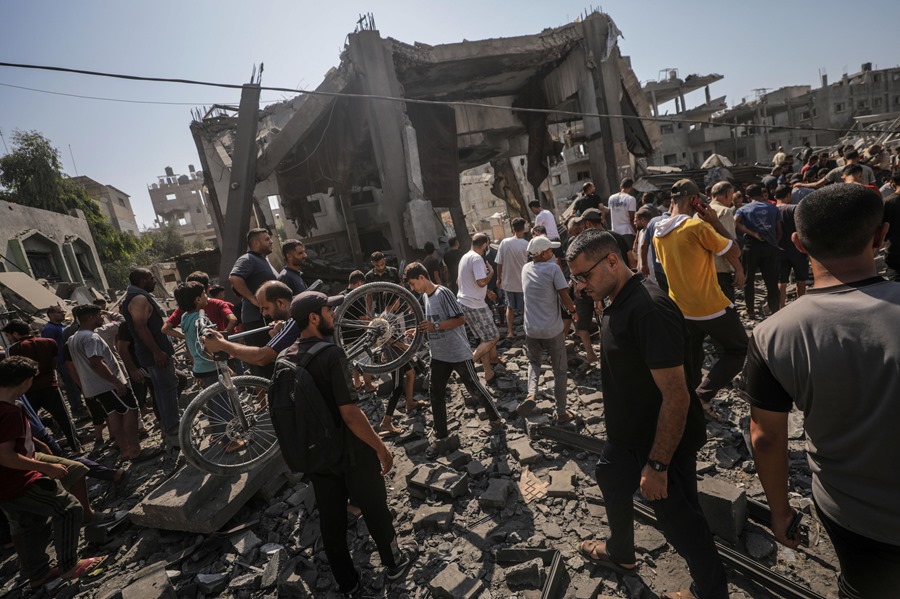 Palestinos buscan a personas desaparecidas bajo los escombros de un edificio destruido tras un ataque aéreo israelí en el campo de refugiados de Al Bureij, en el centro de la Franja de Gaza