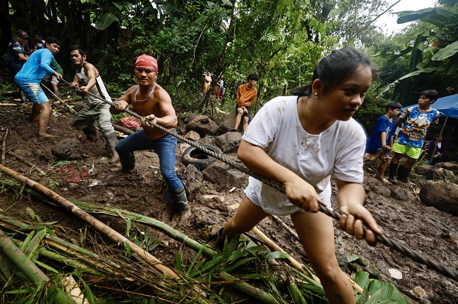 Los aldeanos tiran de una cuerda durante una operación de rescate en una aldea afectada por un deslizamiento de tierra en Antipolo, provincia de Rizal