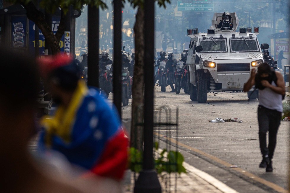 Personas corren durante enfrentamientos entre opositores y miembros de la Guardia Nacional Bolivariana (GNB), en una manifestación tras las elecciones presidenciales, en Caracas (Venezuela). EFE/ Henry Chirinos