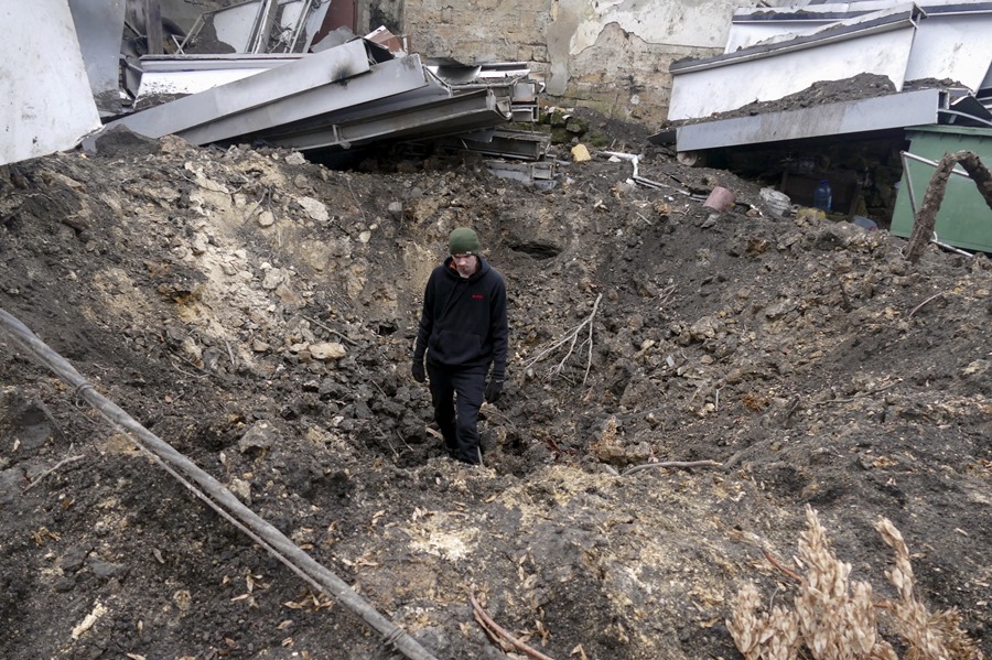 Un hombre se encuentra dentro de un cráter de bombardeo tras un ataque nocturno con drones en Odesa