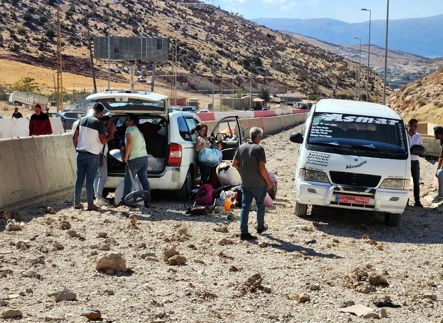 Personas desplazadas que transportaban sus pertenencias entre escombros cerca del cruce fronterizo de Masnaa en el Líbano con Siria