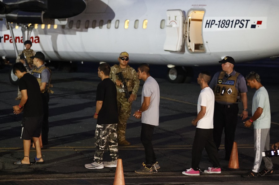 Migrantes caminan frente a un avión tras ser deportados de los Estados Unidos, en el aeropuerto Marcos A. Gelabert en Ciudad de Panam