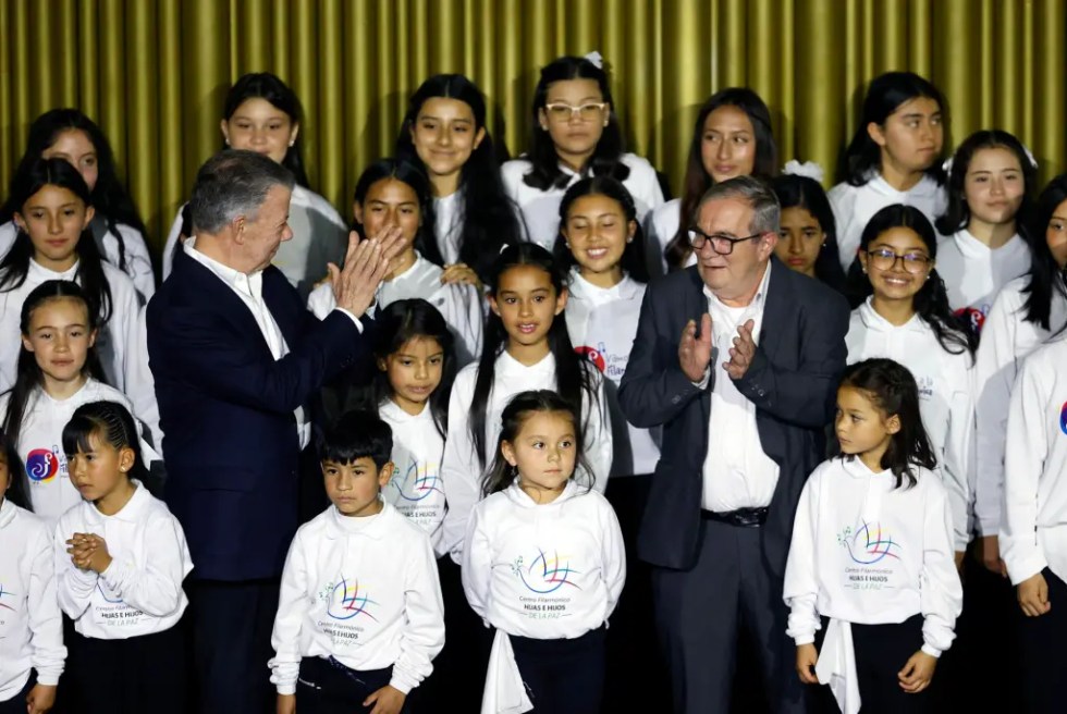 El expresidente de Colombia Juan Manuel Santos (i), junto al líder del partido Comunes y excomandante de la antigua guerrilla de las FARC, Rodrigo Londoño, aplauden junto al "Coro de hijas e hijos por la paz", conformado por niños de los firmantes del acuerdo de paz, durante la conmemoración de los siete años de la firma de ese acuerdo entre Colombia y las FARC, hoy, en el Centro Nacional de Memoria Histórica (CNMH) en Bogotá (Colombia). EFE/ Mauricio Dueñas Castañeda