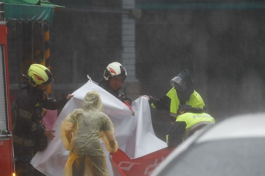 os bomberos y la policía retiran una gran pancarta cuando el tifón Kong-Rey tocó tierra en Hualien