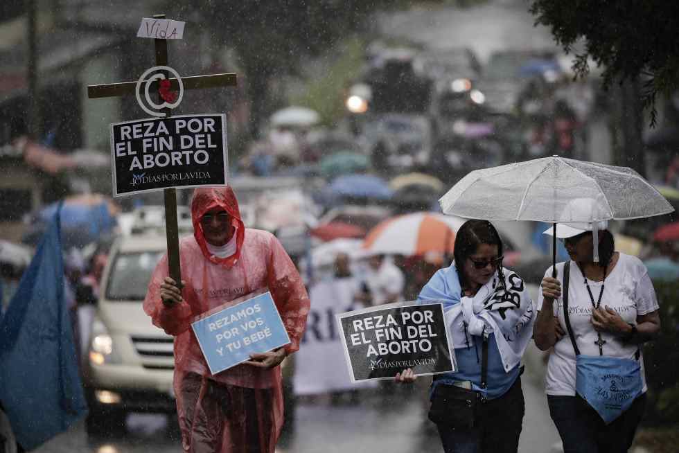 Varias personas muestran mensajes en contra del aborto durante una marcha llamada "Un kilómetro por la vida" rumbo a la CorteIDH, este domingo en San José (Costa Rica). EFE/ Jeffrey Arguedas