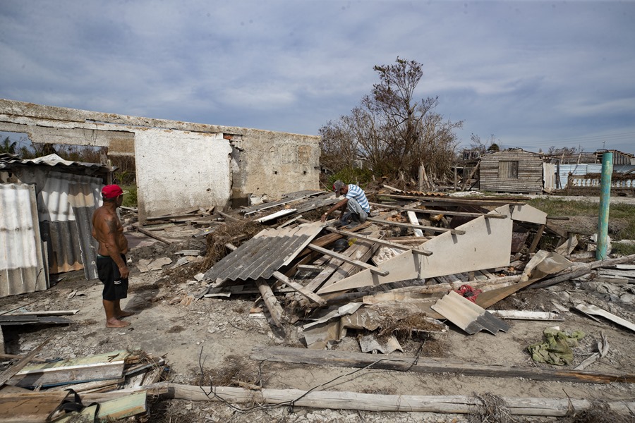 Orlando Moreno (i) y Camilo (d), intentan recoger escombros de su casa destruida por el paso del huracán Rafael en playa Guanimar. EFE/Yander Zamora