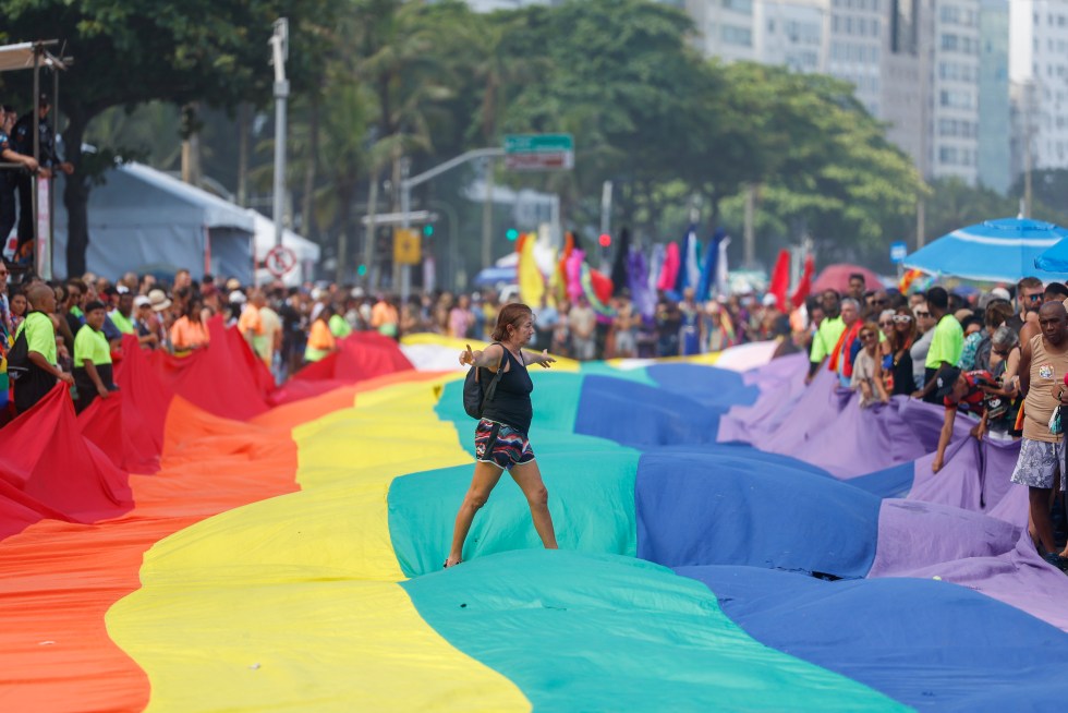 Una persona camina sobre una bandera durante el 'Desfile del Orgullo LGBTIQ+' este domingo en playa de Copacabana, Río de Janeiro (Brasil). EFE/ Antonio Lacerda