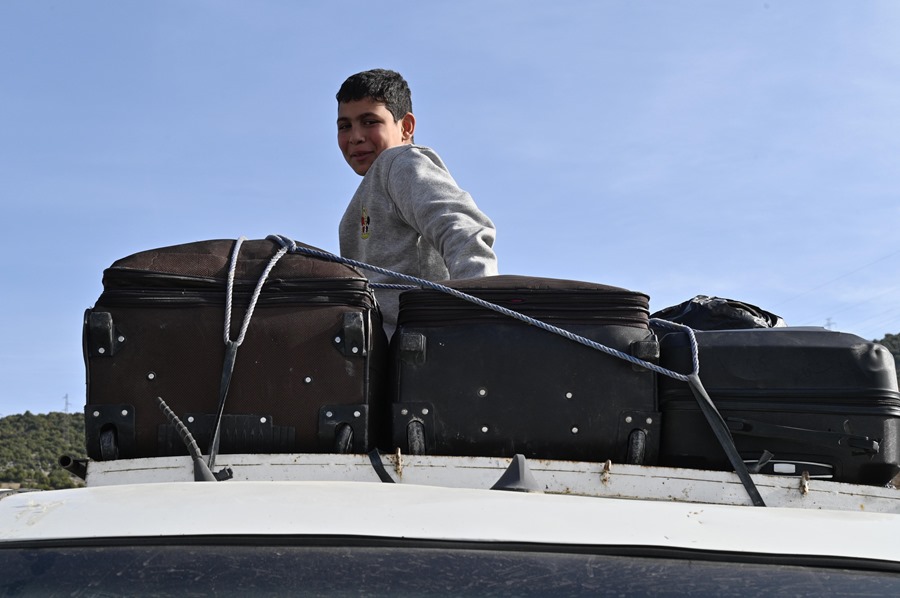 Un niño sirio sobre un coche cargado con maletas en la frontera con Líbano.