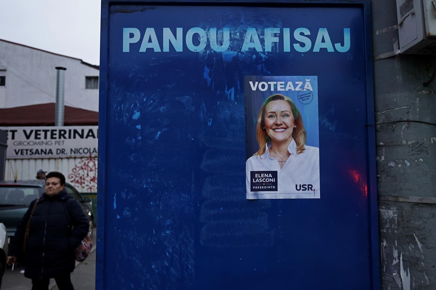 rumaniatiktok Una mujer rumana pasa junto a un tablero vacío que muestra un cartel solitario que representa a la líder del partido Unión Salvar Rumania (USR) y candidata presidencial Elena Lasconi