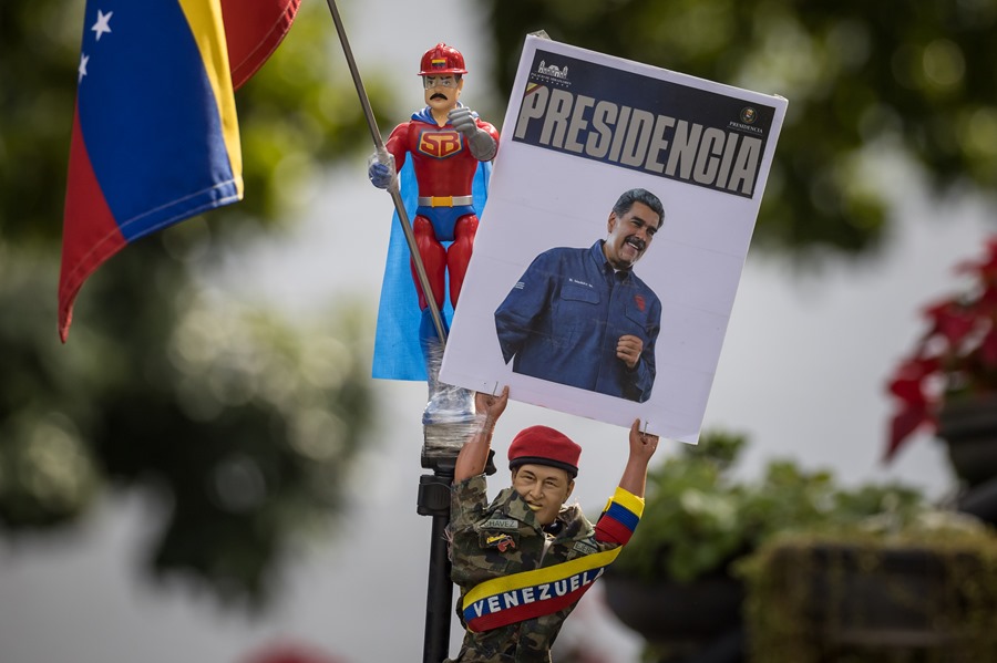 Una persona muestra un muñeco que representa al fallecido presidente de Venezuela Hugo Chávez con un cartel con la imagen del presidente de Venezuela, Nicolás Maduro, en un acto en la Asamblea Nacional (AN, Parlamento) de Venezuela este domingo. EFE/ Miguel Gutiérrez