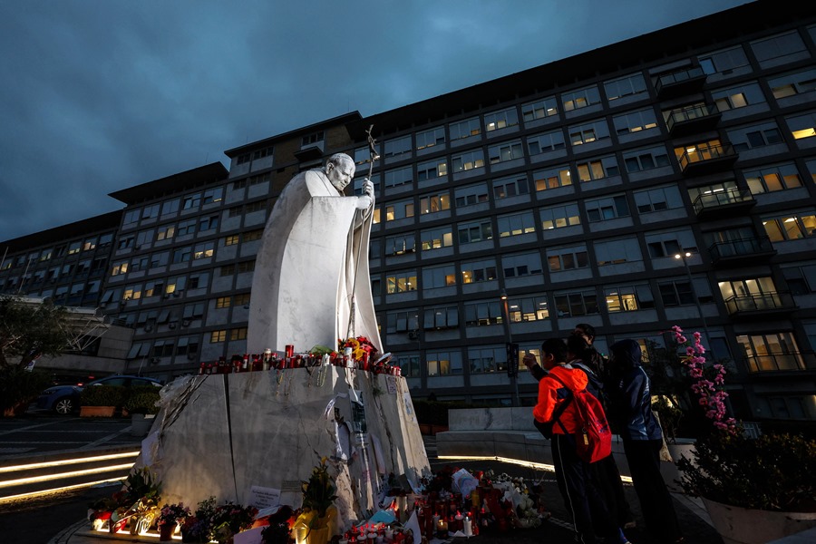 rom02-italy-pope-francis-health-1 Velas y flores se colocan en la base de una estatua del Papa San Juan Pablo II fuera del Hospital Universitario Gemelli en Roma, Italia.